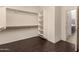 Walk-in closet with dark wood-look floors and built-in shelving and hanging rods at 12221 W Locust Ln, Avondale, AZ 85323