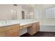 The primary bath features double sinks, wood cabinets, a large mirror, a tub, and a walk-in shower at 1478 E Spur Ave, Gilbert, AZ 85296