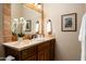 Well-lit bathroom with wood cabinets, decorative mirror, and earth-toned tile at 15123 E Monument Rd, Scottsdale, AZ 85262