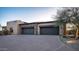 Spacious three-car garage featuring stone accents, a concrete driveway, and desert landscaping at 15123 E Monument Rd, Scottsdale, AZ 85262