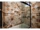 Shower featuring earth-toned tile, glass door, and a built-in shower caddy at 15123 E Monument Rd, Scottsdale, AZ 85262