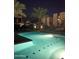 Community pool illuminated at night, surrounded by modern buildings, lush palm trees, and ambient lighting at 1717 E Morten Ave # 2, Phoenix, AZ 85020