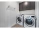 Well-organized laundry room featuring modern washer, dryer, and overhead storage cabinets at 1717 E Morten Ave # 2, Phoenix, AZ 85020