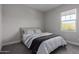 Comfortable bedroom featuring a soft gray bed, striped bedding, and natural light from the window at 21031 W Elm Way Ct, Buckeye, AZ 85396