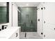 Modern bathroom featuring a glass-enclosed shower with green tile accent and white cabinetry at 3141 E Hillery Dr, Phoenix, AZ 85032