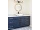 Stylish bathroom with a navy blue vanity, gold hardware, patterned tile flooring, and decorative mirror at 3141 E Hillery Dr, Phoenix, AZ 85032