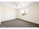 Bright bedroom with a ceiling fan, carpeted floors, and a window showcasing the outdoor view at 3141 E Hillery Dr, Phoenix, AZ 85032