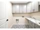 Well-organized laundry room with patterned tile flooring, plenty of cabinet storage, and countertop space at 3141 E Hillery Dr, Phoenix, AZ 85032