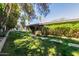 Green backyard with stepping stone pathway surrounded by mature trees and privacy hedges at 3229 E Malapai Dr, Phoenix, AZ 85028