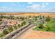 Beautiful aerial view of the community with manicured landscaping, roundabout, and water feature, all under a clear blue sky at 36020 W San Ildefanso Ave, Maricopa, AZ 85138