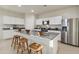 Modern kitchen featuring white cabinetry, a stainless steel refrigerator, and a granite island with stools at 36020 W San Ildefanso Ave, Maricopa, AZ 85138