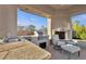 Covered outdoor kitchen boasts stainless steel grill, sink, stone counter, and cozy fireplace with lounge area at 6240 E Ironwood Dr, Scottsdale, AZ 85266