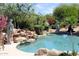 Lushly landscaped pool with rock waterfall feature and surrounding greenery for a private oasis at 6240 E Ironwood Dr, Scottsdale, AZ 85266