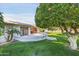 Picturesque backyard with mature landscaping, green grass, and a charming covered patio area at 10825 W Caron Dr, Sun City, AZ 85351