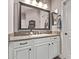 Neutral-toned bathroom features a framed mirror, granite countertop, and white cabinetry at 13211 W Hummingbird Ter, Peoria, AZ 85383
