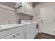 Functional laundry room with sink, cabinets, and modern washer and dryer at 13211 W Hummingbird Ter, Peoria, AZ 85383