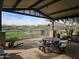 Covered outdoor patio area with picnic table overlooking a green space, perfect for relaxing at 13211 W Hummingbird Ter, Peoria, AZ 85383