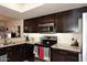 Kitchen area with a stainless steel oven and cooktop with dark cabinets and granite counters and tile backsplash at 13642 S 42Nd St, Phoenix, AZ 85044