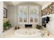 Bathroom featuring a soaking tub with tile surround, shutters and views of the backyard at 15558 W Big Sky Dr, Surprise, AZ 85374