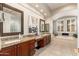 Bathroom featuring granite counters, dual sinks, a soaking tub, shutters and neutral tile flooring at 15558 W Big Sky Dr, Surprise, AZ 85374