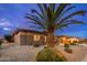 View of the landscaped front yard with gravel, greenery, and a mature palm tree at 15558 W Big Sky Dr, Surprise, AZ 85374