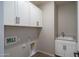 Laundry room with white cabinets, hardware, sink, and tile flooring at 16213 W Soft Wind Dr, Surprise, AZ 85387