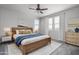 Inviting main bedroom features a wood bed frame, soft lighting, and ample natural light from large windows at 16213 W Soft Wind Dr, Surprise, AZ 85387