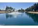 Picturesque community pond featuring a water fountain and lush greenery under a clear blue sky, creating a serene view at 17311 N Kimberly Way, Surprise, AZ 85374