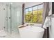 Bright bathroom featuring a soaking tub and glass enclosed shower with marble surround at 2604 N 27Th St # 4, Phoenix, AZ 85008