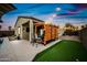 Backyard view with a covered kitchen, artificial grass, and cozy string lights for evening ambiance at 37340 W Merced St, Maricopa, AZ 85138