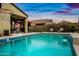 Refreshing backyard pool with a waterfall feature, paired with patio seating, all set against a stunning sunset sky at 37340 W Merced St, Maricopa, AZ 85138