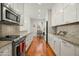 Galley kitchen showcasing granite countertops, stainless steel appliances, and hardwood flooring at 5642 N Scottsdale Rd, Paradise Valley, AZ 85253