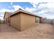 Exterior side view of the property featuring tan stucco and a desert landscape at 8552 S 258Th Dr, Buckeye, AZ 85326