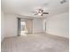 Neutral living room features carpet, ceiling fan and a sliding glass door to patio at 8552 S 258Th Dr, Buckeye, AZ 85326