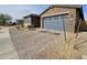 Charming home featuring a paver driveway leading to a blue two-car garage and desert landscaping at , Maricopa, AZ 85138