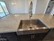 Close-up of a kitchen island featuring granite countertops and a stainless steel farmhouse sink with modern faucet at , Maricopa, AZ 85138