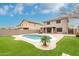 Spacious backyard with a sparkling pool, well-manicured lawn, and a covered patio for outdoor relaxation at 1135 E Desert Holly Dr, San Tan Valley, AZ 85143