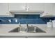 Close up of a kitchen sink featuring white countertops and modern blue tile backsplash at 1180 E Belmont Ave, Phoenix, AZ 85020