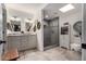 Bright bathroom featuring a double vanity, granite countertops, walk-in shower, skylight, and neutral color palette at 13002 W Castlebar Dr, Sun City West, AZ 85375