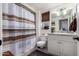 Bathroom featuring a shower with striped curtain, vanity with granite countertop, and woven window shade at 13002 W Castlebar Dr, Sun City West, AZ 85375