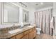 Bathroom featuring dual sinks, granite countertops, framed mirrors, and a patterned shower curtain at 1321 N Bronco Ct, Gilbert, AZ 85233