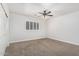 Spacious bedroom with neutral carpet, ceiling fan, and large window with shutters at 1321 N Bronco Ct, Gilbert, AZ 85233