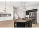 Open kitchen with an island, stainless steel refrigerator, dark cabinetry, and seamless access to the living area and staircase at 1321 N Bronco Ct, Gilbert, AZ 85233