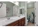 Bathroom features double sink vanity with wood cabinets and a walk in shower with cactus themed shower curtain at 1432 E Pedro Rd, Phoenix, AZ 85042