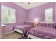 Bright bedroom featuring two twin beds with striped bedding, complemented by light-colored wood flooring and purple walls at 1432 E Pedro Rd, Phoenix, AZ 85042