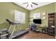 A home office/bedroom features a treadmill, a large screen TV, an olive-green color scheme, and dark wood floors at 1432 E Pedro Rd, Phoenix, AZ 85042
