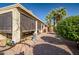 Spacious backyard featuring a covered patio, desert landscaping, and mature palm trees at 16875 W Manchester Dr, Surprise, AZ 85374