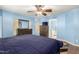 The bright primary bedroom showcases wooden furniture, a ceiling fan, and access to an ensuite bathroom at 19863 N Emmerson Dr, Maricopa, AZ 85138