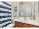 Well-lit bathroom with a toilet, bathtub with a blue and white curtain, and vanity at 22157 W Moonlight Path, Buckeye, AZ 85326