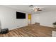 Spacious living room featuring wood floors, a ceiling fan, and a large mounted television for relaxation and entertainment at 2230 W Peralta Ave, Mesa, AZ 85202